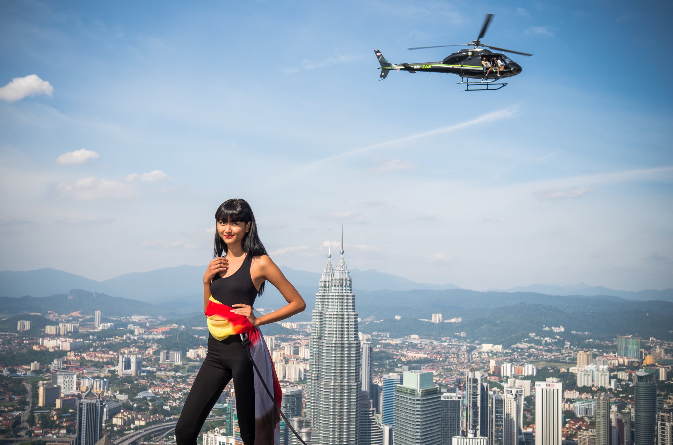 An Asia’s Next Top Model contestant posing above Kuala Lumpur as a helicopter passes
